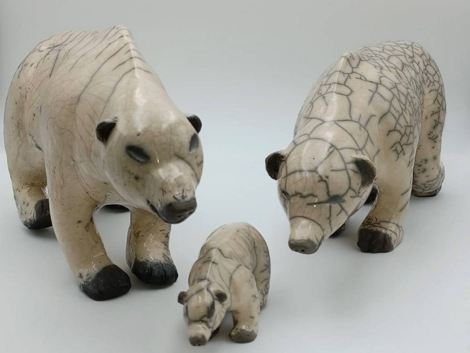 Drei aus Keramik gefertigte Eisbären-Figuren vor weißem Hintergrund.