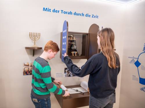 Zwei Personen betrachten Ausstellungsstücke im Haus der Religionen