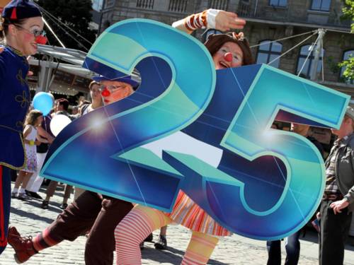 Eine Gruppe der Dienstagsclowns aus Hannover positioniert sich um eine große "25".