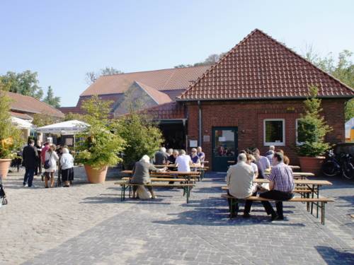 Gepflasterter Hof, im Hintergrund Gebäude aus roten Backsteinen. Menschen sitzen auf Festzeltgarnituren.