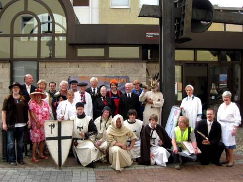 24 Personen posieren für ein Gruppenfoto vor dem Kreismuseum in Peine, jeder und jede trägt das Kostüm einer historischen Peiner Persönlichkeit, darunter sind zum Beispiel Soldaten, Handwerker und Künstler.
