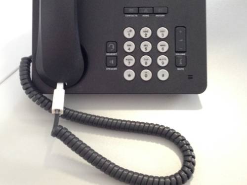 Ein schwarzes altes Telefon mit Tasten und verkabeltem Hörer.