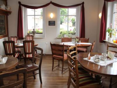 Blick in ein Caf&eacute; mit alten Holzst&uuml;hlen und Tischen, wei&szlig;en Deckchen und Milch und Zucker auf den polierten Tischen