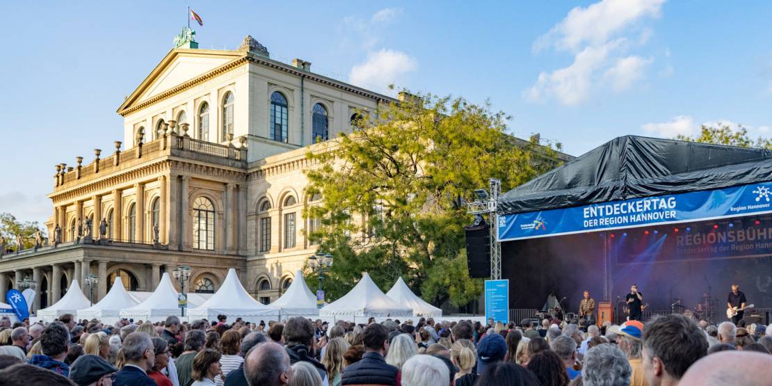 Die Oper in Hannover mit einer Bühne und vielen Menschen auf dem Platz davor.