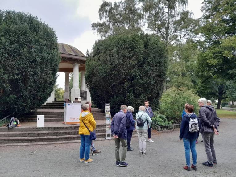 Eine Menschengruppe trifft sich zu einer Führung in einem Park