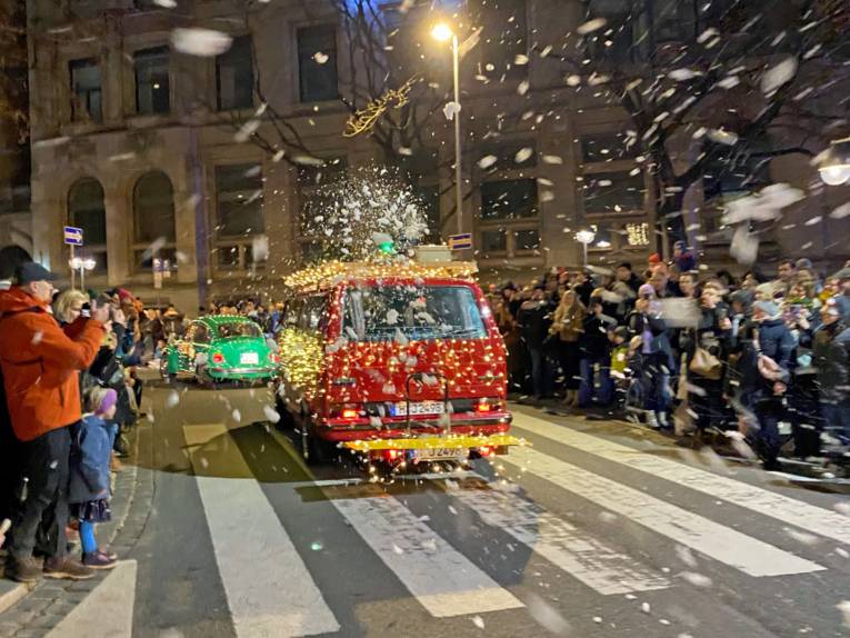 Mit Weihnachtslichterketten geschmückter alter VW-Bulli und VW-Käfer.