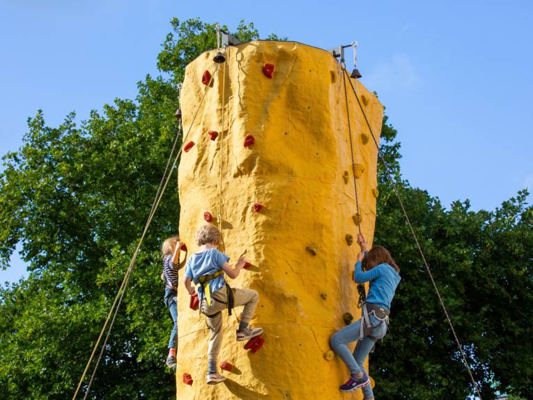 3 Kinder klettern hoch oben einen Kletterturm hinauf