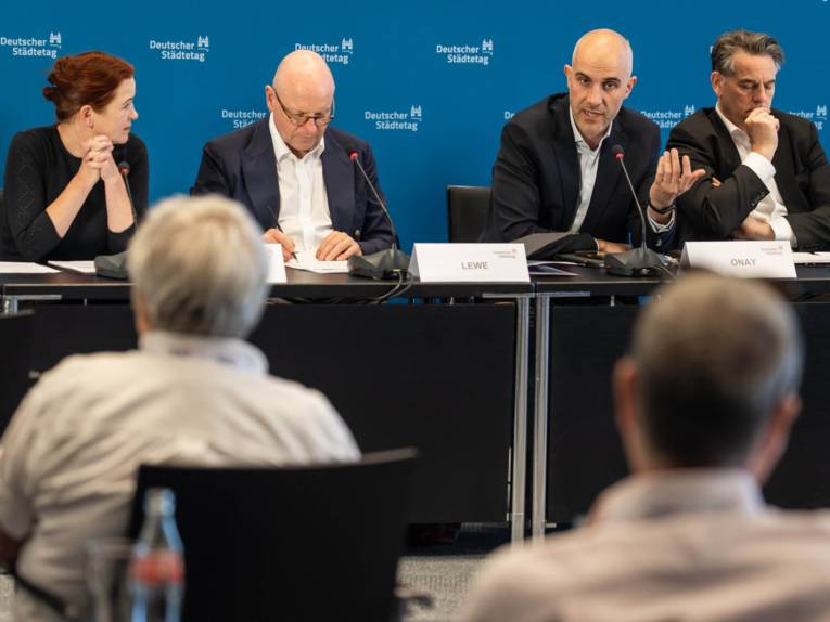 Vier Personen bei einer Pressekonferenz.