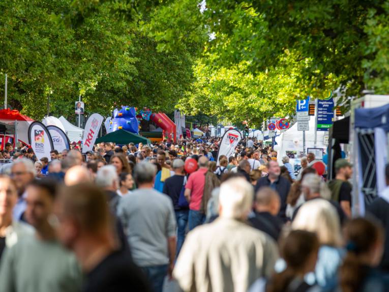 Eine Straße mit vielen Menschen, Beachflags, Pavillons und einer Hüpfburg