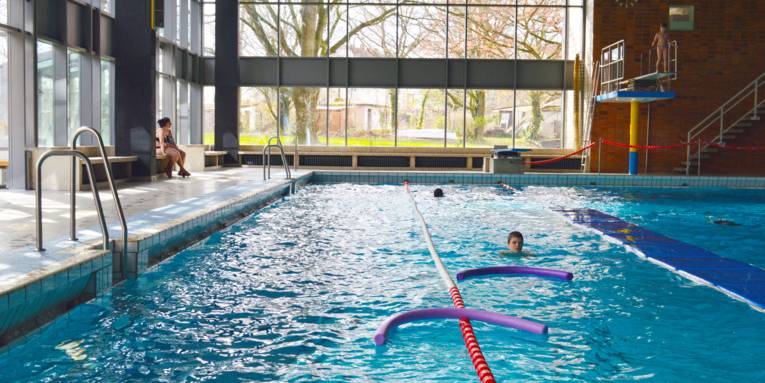 Schwimmbecken mit Schwimmern, Poolnudeln und Bahnbegrenzungen