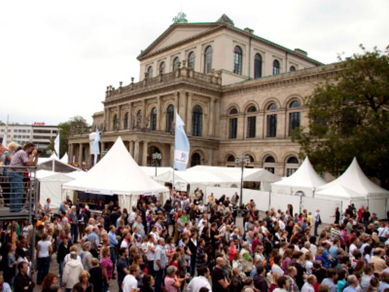 Vor dem Opernhaus in Hannover stehen weiße Pagodenzelte, eine große Menschenmenge füllt den Opernplatz.