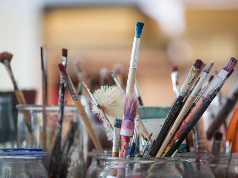 Mehrere Gläser, in die viele Pinseln in unterschiedlichen Größen und Formen reingestellt sind.