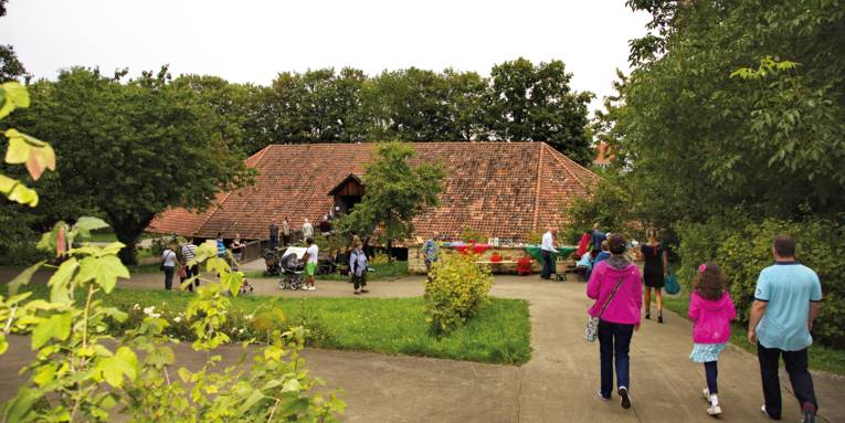 Menschen gehen im Willy-Spahn-Park spazieren, Stände sind aufgebaut.