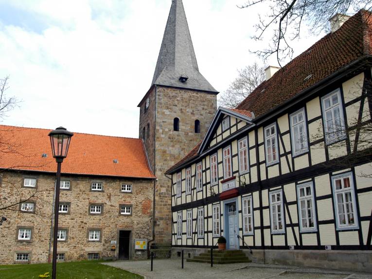 Blick auf die Klosterkirche mit romanischem Wehrturm, Rechts ist ein benachbartes Fachwerkgebäude zu sehen. 