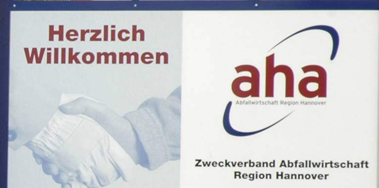 Schild mit der Aufschrift "Herzlich Willkommen" und dem Logo der von "aha"