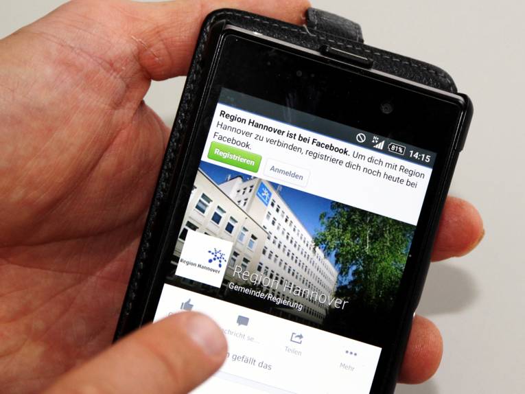 Jemand bedient sein Smartphone und ruft den Auftritt der Region Hannover bei facebook auf: facebook.com/hannoverregion