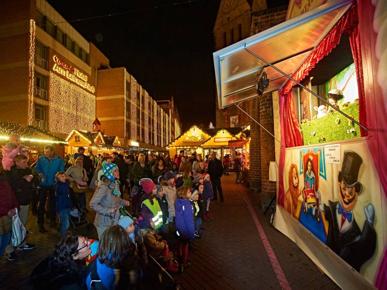 Eltern und Kinder verfolgen gespannt das Geschehen auf der Puppenbühne am Marktplatz