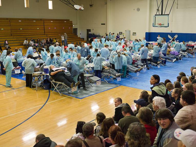 20 Zahnartzstühle mit Patienten und Ärzteteams in einer Sporthalle 