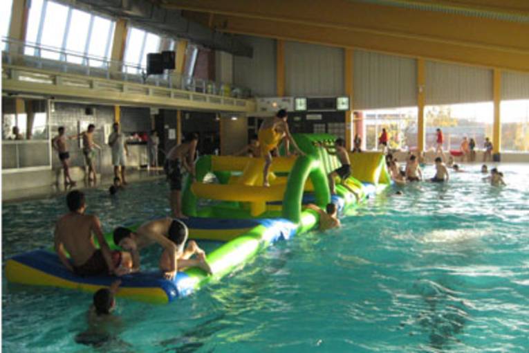 Kinder, die im Hallenbad auf dem aufblasbaren Wasserspielgerät "Wibit" spielen