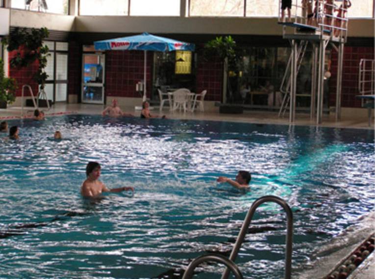 Jugendliche im Wasser und auf dem Sprungturm im Hallenbad