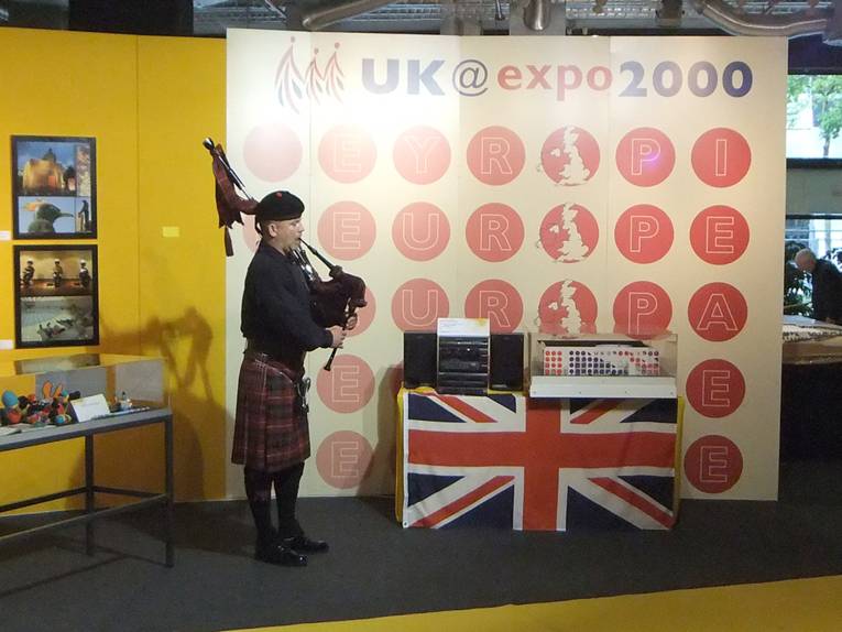 Ein Dudelsackspieler vor einigen britischen Ausstellungsstücken von der EXPO 2000