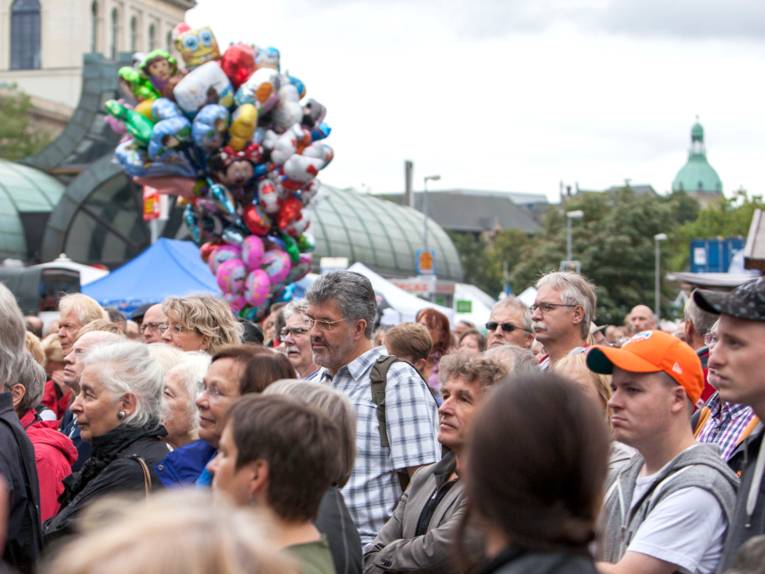 Viele Menschen füllen den Platz am Kröpcke, im Hintergrund steigt eine Traube mit bunten Heliumballons in den Himmel.