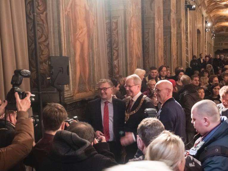 Menschenmengen um zwei Männer in einer Galerie.