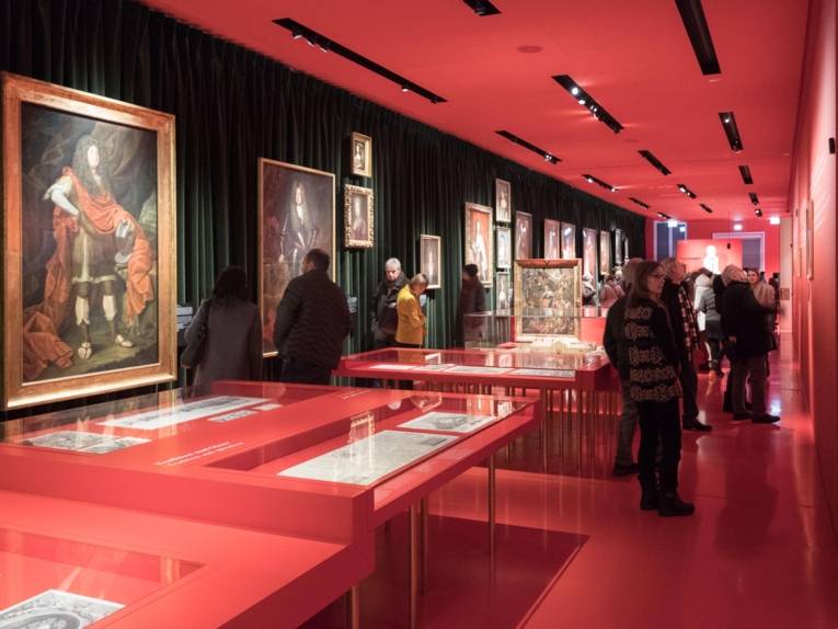 Menschen in einem rot eingerichteten Museum. 