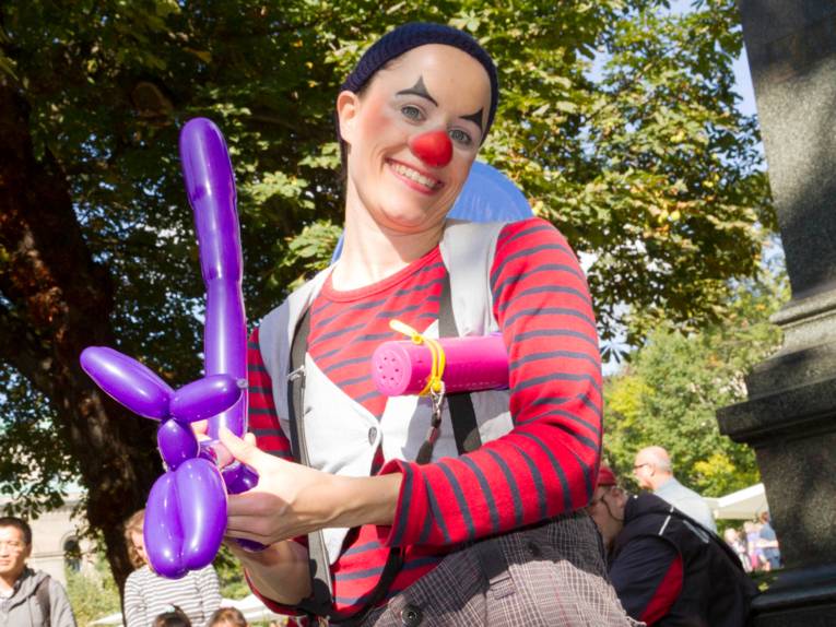 Eine Clownin knotet einen Hund aus einem Luftballon.