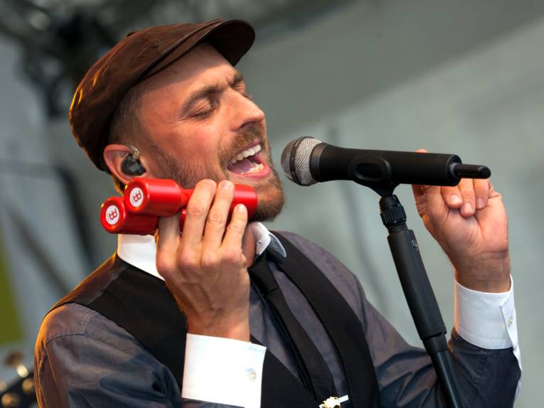 Ein Mann steht hinter einem Mikrofon und singt.