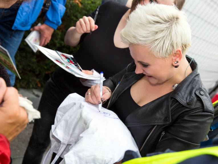 Die blonde Frontfrau von Elaiza schreibt mit einem Filzstift auf einen weißen Stoffbeutel.