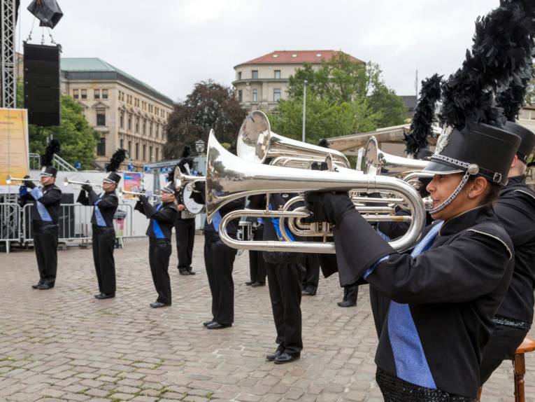 Musiker tragen eine Uniform in den Farben Blau und Schwarz und spielen auf Blechblasinstrumenten.