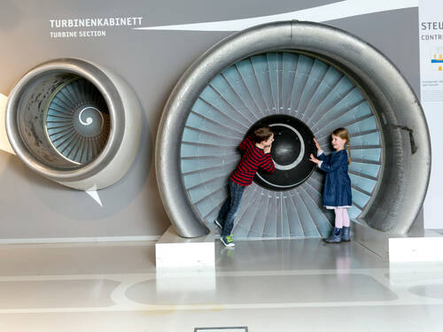 Kinder schauen sich Flugzeugkabinen im Ausstellungsraum aus der Nähe an. Kinder schauen sich Flugzeugkabinen im Ausstellungsraum aus der Nähe an.
