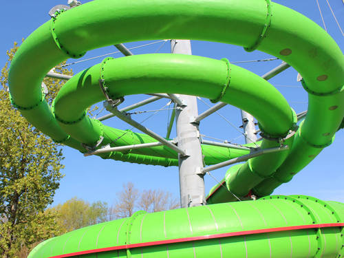 Zwei grüne Röhren einer Wasserrutsche bilden eine kurvige Rutschstrecke. Zwei grüne Röhren einer Wasserrutsche bilden eine kurvige Rutschstrecke.