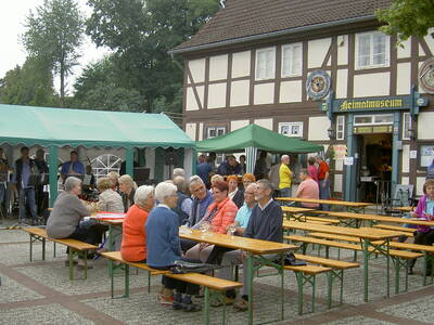 Menschen sitzen auf Festzeltgarnituren vor einem Fachwerkhaus. Menschen sitzen auf Festzeltgarnituren vor einem Fachwerkhaus.