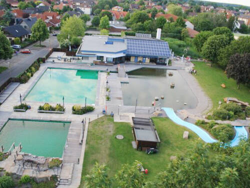 Drei Schwimmbecken unter freiem Himmel, eine Rutsche mündet in einem der Becken Drei Schwimmbecken unter freiem Himmel, eine Rutsche mündet in einem der Becken