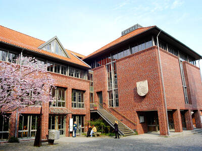 Großer Backsteinbau mit vielen Fenstern. Der blühende Kirschbaum lässt vermuten, dass das Bild im Frühjahr aufgenommen wurde. Großer Backsteinbau mit vielen Fenstern. Der blühende Kirschbaum lässt vermuten, dass das Bild im Frühjahr aufgenommen wurde.