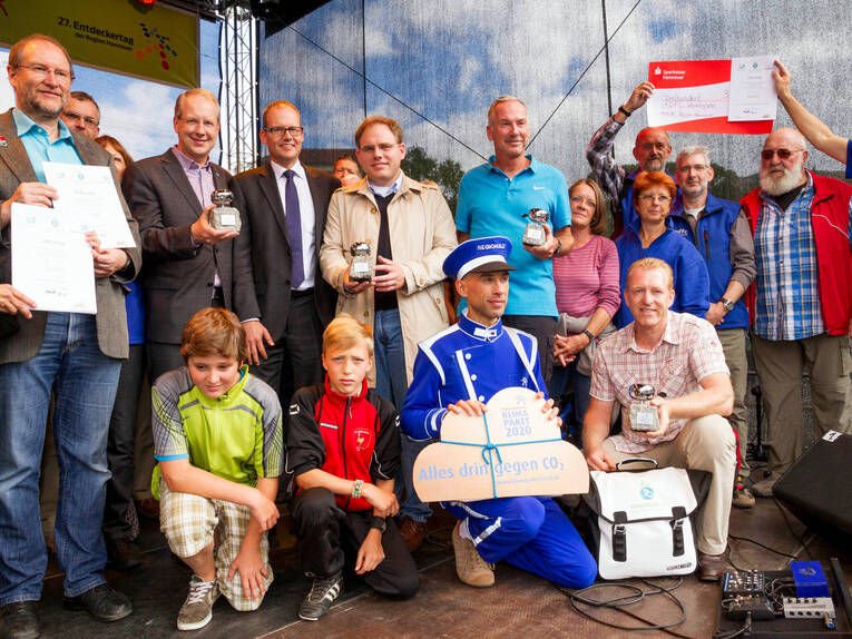 Viele Menschen haben sich auf einer Bühne zu einem Gruppenfoto augestellt. Viele Menschen haben sich auf einer Bühne zu einem Gruppenfoto augestellt.