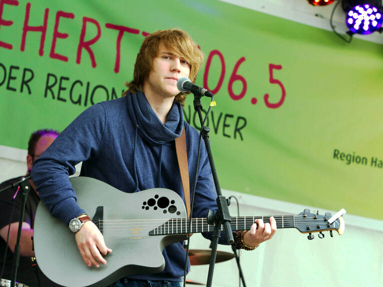 Ein Mann mit einer Gitarre steht hinter einem Mikrofon. Ein Mann mit einer Gitarre steht hinter einem Mikrofon.